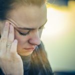 A distressed woman holds her head, conveying the pain of unmet emotional needs in a relationship.