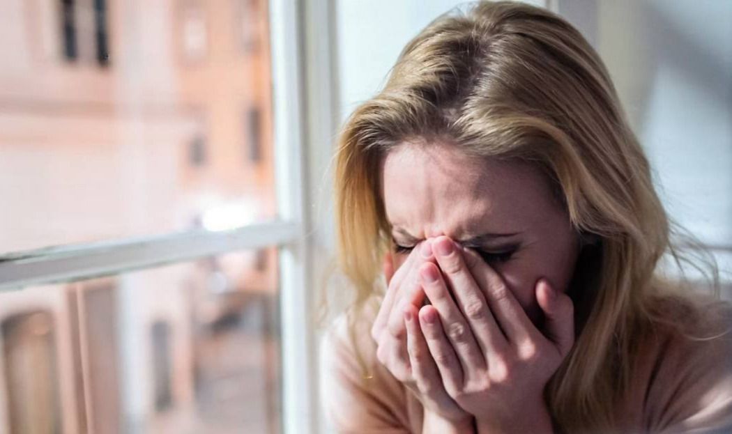 A woman in tears at a window, representing vulnerability, used as a banner for a relationship coaching website.